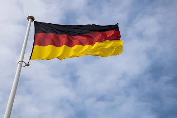 Almanya 'yı, birliği ve ulusal gururu simgeleyen açık gökyüzü, siyah, kırmızı ve altın çizgilere karşı rüzgarda dalgalanan Alman ulusal bayrağı.
