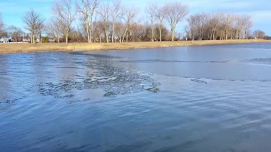 Baharda eriyen buzla kısmen donmuş göl. Mavi gökyüzü ve su dalgalarıyla kıştan ilkbahara geçiş. Chicago, Illinois 'de bahar buzları çözülüyor. Eriyen buz ve mavi gökyüzü ile kısmen donmuş göl.