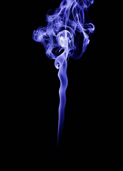 The smoke of incense stick are burning on the black background.