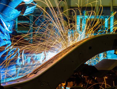 Endüstri işçisi otomotiv parçası fabrikasında kaynak yapıyor.