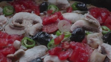 Taze malzemelerle hazırlanmış ve fırına yerleştirilmeye hazır pişmemiş bir pizzanın yakın çekimi