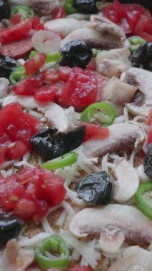 Taze malzemelerle hazırlanmış ve fırına yerleştirilmeye hazır pişmemiş bir pizzanın yakın çekimi