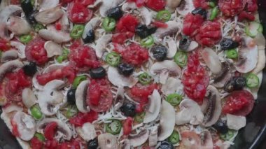 Taze malzemelerle hazırlanmış ve fırına yerleştirilmeye hazır pişmemiş bir pizzanın yakın çekimi