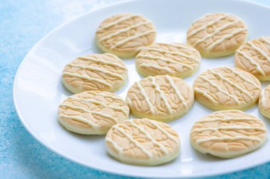 Temiz beyaz tabakta servis edilen limonlu beyaz çikolatalı kurabiyelerin yakın çekimi.