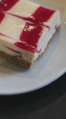 Kare şekilli ahududu peynirli keki kremalı ve taze meyveli kekle yakın plan.