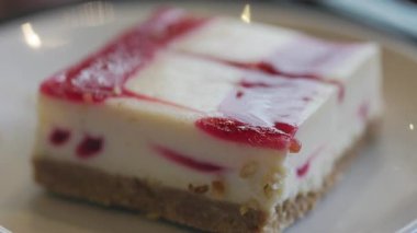 Kare şekilli ahududu peynirli keki kremalı ve taze meyveli kekle yakın plan.