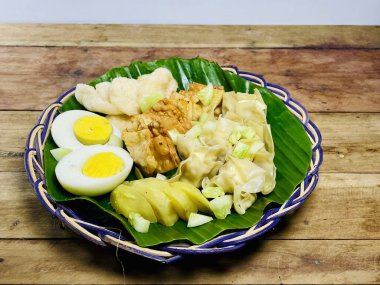 Batagor Siomay, yarım dilimlenmiş yumurta ve krakerlerle birlikte muz yapraklarıyla örülü bir tabakta servis edildi. Endonezya mutfağına estetik bir cazibesi var..