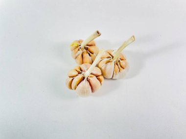 Beyaz arka planda üç baş sarımsak (Allium sativum) bulunur. Her kafa, kağıt kaplamalı, açık tenli, açık beyaz karanfillerden oluşur. Sarımsak sapları, hafif kurumuş ve sert, başlarının üst kısmından çıkıntılı.