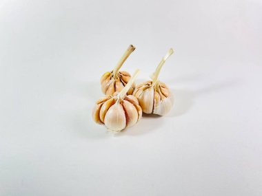 Beyaz arka planda üç baş sarımsak (Allium sativum) bulunur. Her kafa, kağıt kaplamalı, açık tenli, açık beyaz karanfillerden oluşur. Sarımsak sapları, hafif kurumuş ve sert, başlarının üst kısmından çıkıntılı.