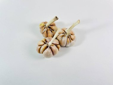 Beyaz arka planda üç baş sarımsak (Allium sativum) bulunur. Her kafa, kağıt kaplamalı, açık tenli, açık beyaz karanfillerden oluşur. Sarımsak sapları, hafif kurumuş ve sert, başlarının üst kısmından çıkıntılı.