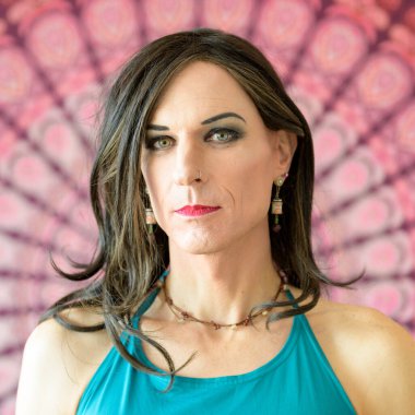 Renkli bir arkaplan önünde ciddi duyguları olan transseksüel bir adamın kare portresi.