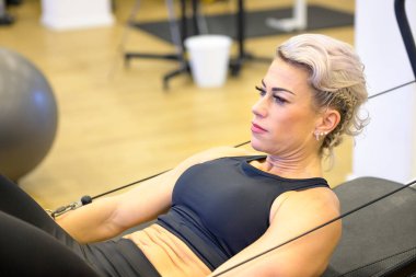 Spor salonunda kaslarını güçlendirmek için direnç eğitimi alan sağlıklı bir kadın sağlık ve zindelik kavramına yakın bir bakış açısıyla.