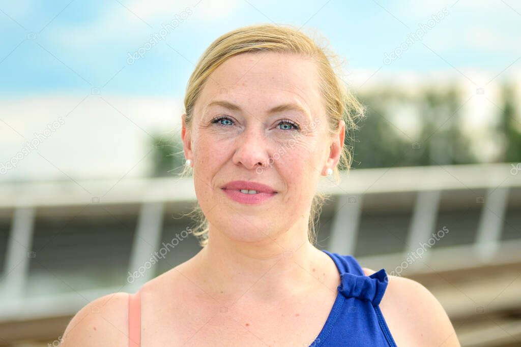 Close up of a thoughtful middle-aged woman looking quietly at the camera with a pensive smile