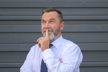 Bir iş adamı ciddi bir konsantrasyonla kafasını kaldırıp bir sorunu düşünürken ya da bir strateji planlarken parmakları dudaklarına kadar derin düşüncelere dalmış.