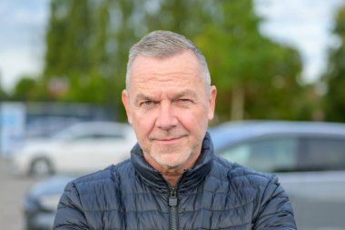 Siyah ceketli olgun bir adamın resmi. Ciddi bir yüz ifadesiyle kameraya özgüvenle bakıyor..