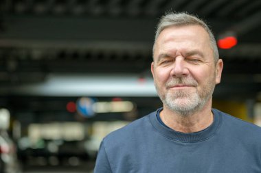 Rahat olgun bir adam kapalı gözlerle evde duruyor, sakinliğini, farkındalığını ve şehir ortamında kendine güvenini iletiyor..