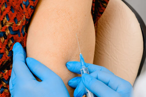 Oudere vrouw die een coronavirusvaccin krijgt. Griepvaccin injecteren in de arm van de patiënt — Stockfoto