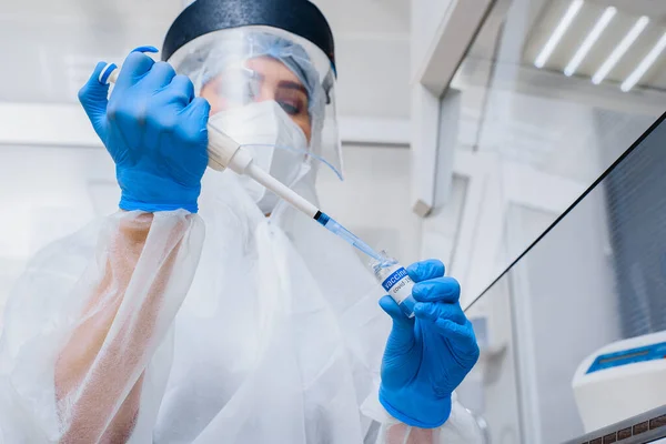 Laboratoriumassistent in een beschermend pak en masker met dispenser en koel vaccin in zijn handen — Stockfoto