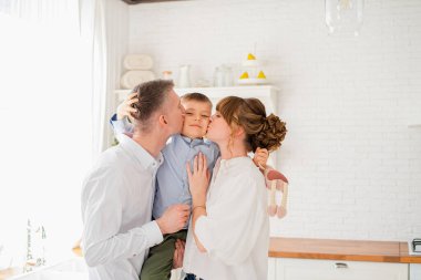 Genç mutlu ebeveynler küçük oğullarını öperler. Mutlu genç aile