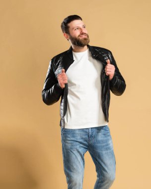 Pastel turuncu stüdyo arka planında siyah ceketli beyaz tişörtlü yakışıklı bir adam. Tişört modeli..