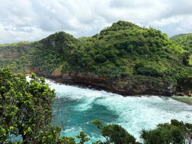 Parlak mavi gökyüzünün altında kıyı uçurumları ve turkuaz okyanus dalgalarının manzarası. Seyahat ve turizm içeriği, doğa başyazıları, manzara geçmişi, açık hava macera temaları ve refah veya rahatlama görselleri için uygundur.