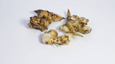 Dilimlenmiş taze galangal manzarası temiz beyaz bir arka planda düzenlenmiş ve izole edilmiş. Endonezya ve Güneydoğu Asya mutfağında yaygın olarak kullanılan doğal aromatik tropik baharat, bitkisel tıp ve geleneksel sağlık ilaçları.