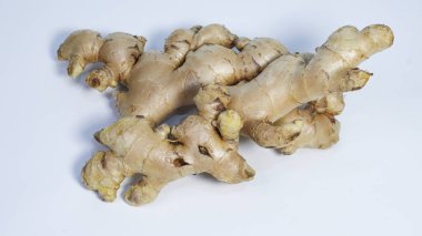 Temiz beyaz arka planda izole edilmiş taze zencefil kökü yakın plan. Doğal aromatik baharat yemek pişirmede, bitkisel içeceklerde, geleneksel tıpta ve Asya mutfağında sağlıklı yaşam kavramlarında yaygın olarak kullanılır..