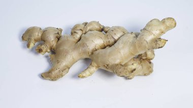 Temiz beyaz arka planda izole edilmiş taze zencefil kökü yakın plan. Doğal aromatik baharat yemek pişirmede, bitkisel içeceklerde, geleneksel tıpta ve Asya mutfağında sağlıklı yaşam kavramlarında yaygın olarak kullanılır..