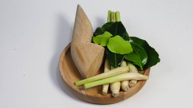 Taze limon otu sapları, galangal kökü ve beyaz stüdyo arka planında izole edilmiş ahşap bir tabakta kaffir limon yaprakları. Geleneksel Güneydoğu Asya aşçılık otları Tayland ve Endonezya mutfağında yaygın olarak kullanılır.