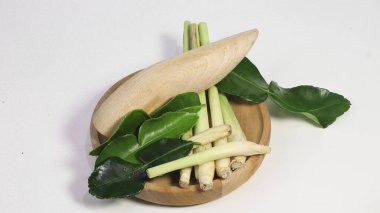 Taze limon otu sapları, galangal kökü ve beyaz stüdyo arka planında izole edilmiş ahşap bir tabakta kaffir limon yaprakları. Geleneksel Güneydoğu Asya aşçılık otları Tayland ve Endonezya mutfağında yaygın olarak kullanılır.