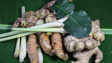 Jamu olarak bilinen geleneksel Endonezya bitkisel içeceğinin üst görüntüsü muz yaprağında taze zerdeçal, zencefil ve doğal malzemelerle servis ediliyor. Geleneksel tıp, sağlık ve doğal besinleri temsil eden sağlıklı organik içecek.