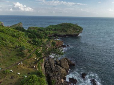 Bereketli yeşil tepeler, dramatik kayalık uçurumlar ve parlak ve berrak bir gökyüzünün altındaki derin mavi okyanus sularının bulunduğu tropikal bir kıyı şeridinin güzel hava manzarası. Doğal deniz manzarası seyahat, turizm, doğa geçmişi ve açık hava macera temaları için idealdir.