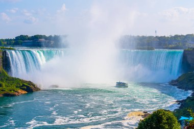 Niagara Şelalesi 'ndeki Horseshoe Şelalesi' nin geniş panoramik manzarası ve devasa şelaleye yaklaşan bir gezi teknesi. Niagara Şelalesi, Kanada - 19 Eylül 2024.