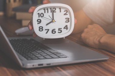 Çalışma masasında masa saati tutuyor.