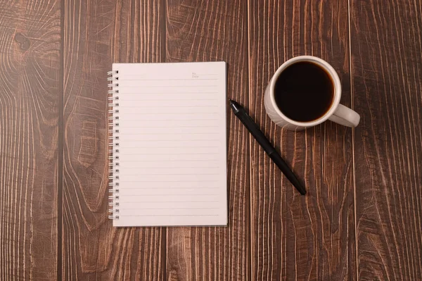 机の上にコーヒーとノートがあります — ストック写真