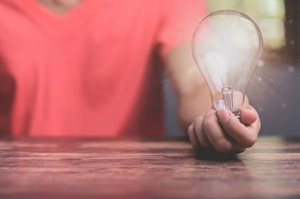 hand of a man with a light bulb And there is a gear icon