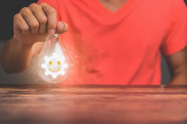 hand of a man with a light bulb And there is a gear icon