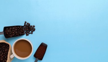 Kahve fincanı, kahve çekirdekleri, mavi arka planda öğütülmüş kahve.