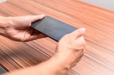 El, masadaki akıllı telefonu kullanıyor.