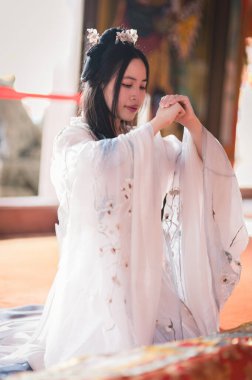 Geleneksel bir Çinli gibi giyinmiş, sakin bir atmosfere dalmış genç bir kadın. Karmaşık detaylar kültürel mirası ve zarafeti yansıtıyor..