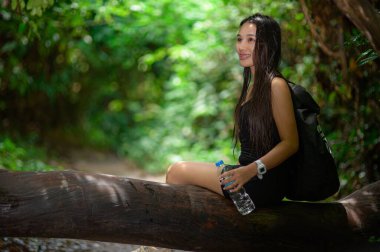 Bir kadın yemyeşil bir ormanda yürürken doğanın huzurunun tadını çıkarır. Bir kütüğün üzerinde oturmuş, elinde bir su şişesi tutuyor, macera ve sükuneti kucaklıyor..