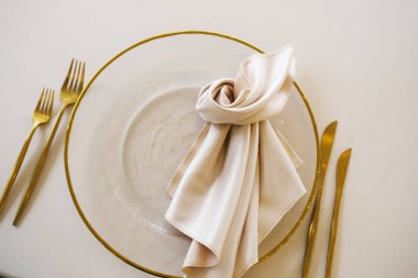 Sofistike yemek düzenlemeleri altın kenarlı, hafif kumaş peçeteli ve altın çatal bıçaklı temiz bir tabak sergiliyor. Özel durumlar için zarif sofra düzenini geliştiriyor.