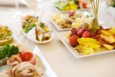 Beyaz tabaklar üzerinde canlı bir taze meyve ve gurme tabağı, doku ve renklerin altını çizmek, aşçılık zevki için davetkar bir atmosfer yaratmak.