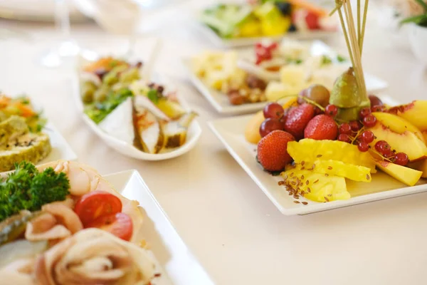 Beyaz tabaklar üzerinde canlı bir taze meyve ve gurme tabağı, doku ve renklerin altını çizmek, aşçılık zevki için davetkar bir atmosfer yaratmak.