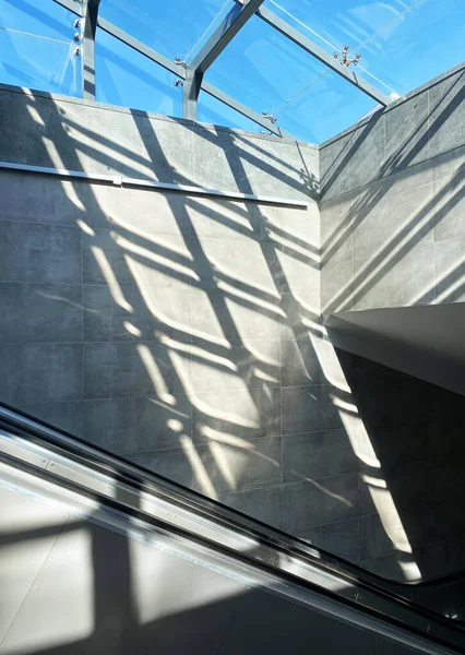 Mimari iç mekan, güneş ışığıyla yürüyen merdiveni sergiliyor beton duvarlar ve cam tavan üzerinde güzel gölgeler yaratarak modern tasarım ve atmosferi geliştiriyor.