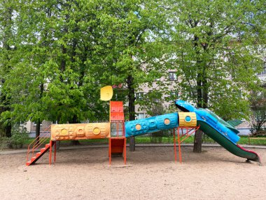 Yeşil ağaçlarla çevrili, canlı bir kaydırak ve tırmanma çerçevesi olan oyun parkı, çocuklar için eğlenceli bir açık hava alanı sağlıyor.