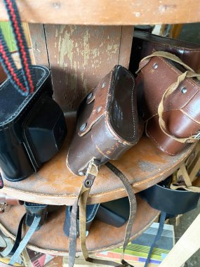 Deri kamera kılıfları farklı renkte ve stillerde bir vintage mağazasında ahşap bir vitrin tezgahında düzenlenir.