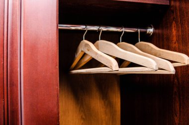 Ahşap askılar ahşap bir gardıroptaki krom bir çubukta sergilenir, parlak kahverengi bir kaplama ve temiz bir iç mekan sergilenir.