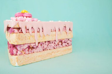 Pembe kremalı köpüklü kek dilimi ve şeker süslemeleri, yaratıcı tasarım ve görsel hikaye anlatımı için geniş bir kopya alanı sağlayan turkuaz arka planda bulunuyor.