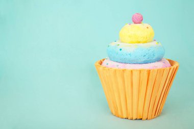 Pastel renkli krema katmanları ve açık mavi arkaplan üzerine sarı kağıt kaplamalı süslemeli kek.